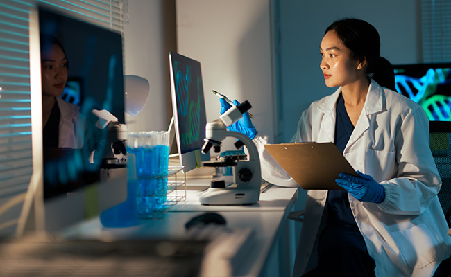 Doctor in the lab double checking her research on clipboard to the computer findings.