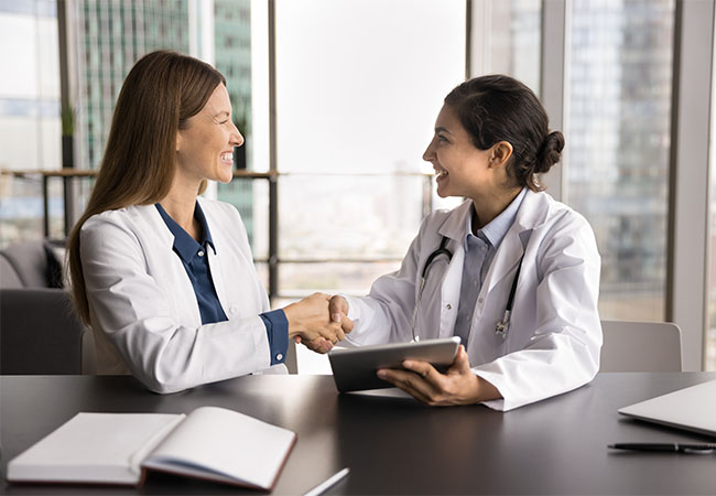 Partnership,In,Patient,Care.,Two,Happy,Smiling,Diverse,Women,Medical doctor shaking hands with another doctor