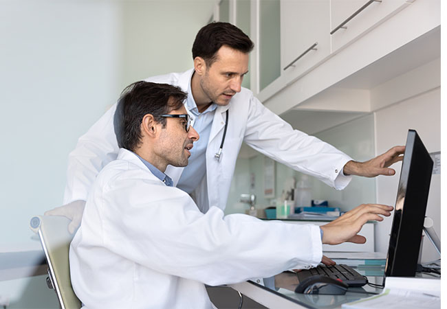 Two,Medical,Professionals,Meeting,And,Talking,At,Work,Computer,In